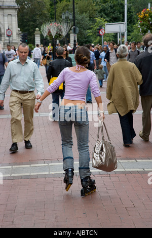 Giovane donna pattinaggio tra la folla su una strada Foto Stock