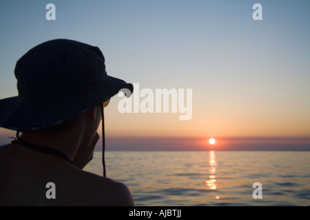 Silhouette di un giovane uomo di godersi il tramonto Foto Stock