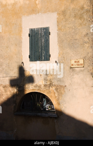 Ombra della croce su edificio di fronte alla chiesa in Rue de l'Eglise, Rousillon Foto Stock