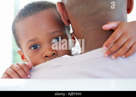 Ritratto di un ragazzo africano guardando sopra di suo padre a spalla Foto Stock