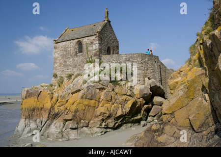Piccola chiesa di pietra su sperone di roccia dietro il Mont Saint Michel Bretagna Francia Foto Stock
