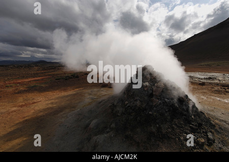 Fumante o fumarola in un paesaggio geotermica con una vista di lontane colline a Hverarond vicino a Myvatn Nord Islanda Foto Stock