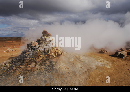 Fumante o fumarola in un paesaggio geotermica con una vista di lontane colline a Hverarond vicino a Myvatn Nord Islanda Foto Stock