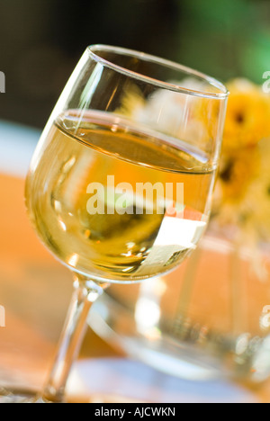 Bicchiere di vino bianco con fiori di primavera seduta sul tavolo Foto Stock