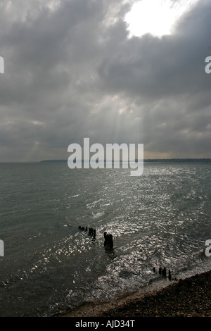 Acqua di Southampton, groyne in legno e la spiaggia di ciottoli insieme contro un imponente cielo a Calshot Spit, Calshot, Hampshire Foto Stock