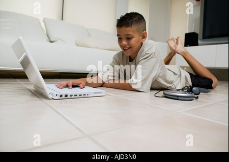 Boy utilizzando laptop sul pavimento nel soggiorno, vista terra Foto Stock