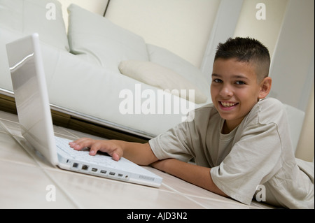 Boy utilizzando laptop sul pavimento nel soggiorno, vista terreno, ritratto Foto Stock