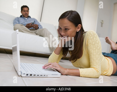 Donna sdraiata sul pavimento con il laptop in soggiorno, vista terra Foto Stock