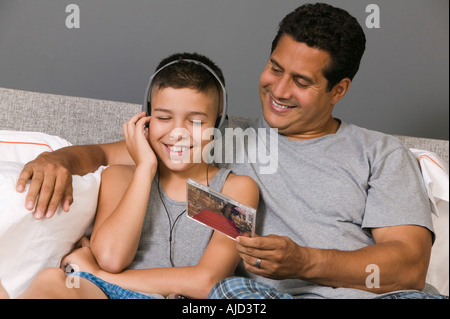 Padre e Figlio ascoltando la musica seduto sul letto Foto Stock