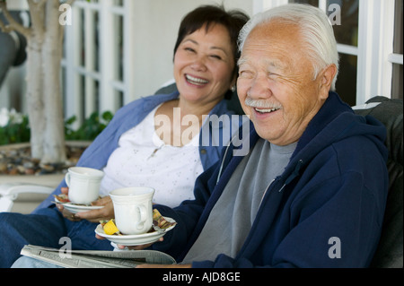 Coppia senior bere il tè sulla veranda, sorridente Foto Stock