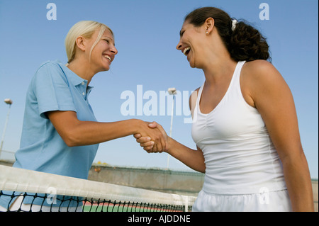 Due femmina i giocatori di Tennis agitando la mano su campo da tennis net, basso angolo di visione Foto Stock