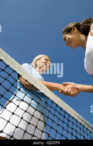 Due femmina i giocatori di Tennis agitando la mano su campo da tennis net, basso angolo di visione Foto Stock