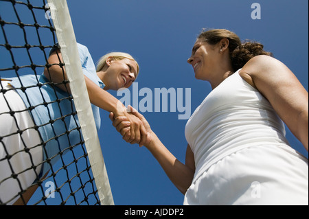 Due femmina i giocatori di Tennis agitando la mano su campo da tennis net, basso angolo di visione Foto Stock