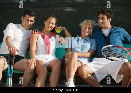 Quattro doppi misti tennis giocatori seduti sul banco a tennis, ritratto Foto Stock