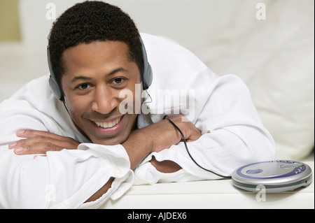L'Uomo sdraiato sul divano ascolto di musica sul lettore CD portatile, ritratto Foto Stock