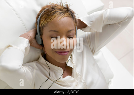 Donna sdraiata sul divano ascolto di musica sul lettore CD portatile, vicino, vista aerea Foto Stock