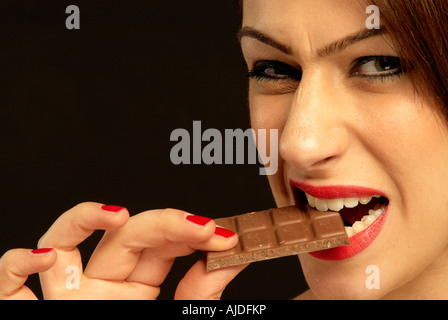 Donna di mordere in una barretta di cioccolato Foto Stock