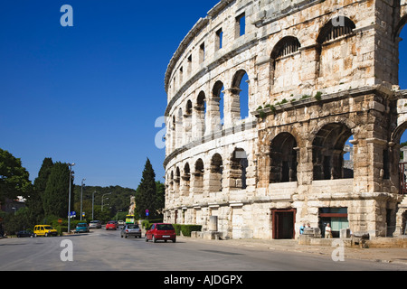 Il traffico della strada passa sulla strada di sotto le mura di pietra del Colosseo Arena di Pola Croazia. Foto Stock