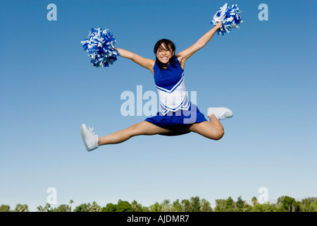 Sorridente Cheerleader jumping a mezz aria (verticale). Foto Stock