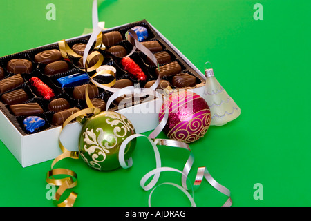 Una scatola di finissimo cioccolato su sfondo verde palle di Natale e decorazioni Foto Stock