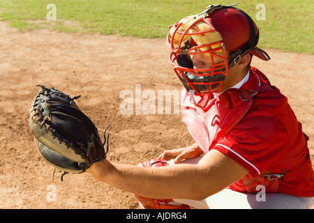 Il baseball catcher accovacciato sul campo di baseball Foto Stock