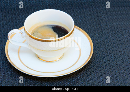 Una bella tazza cinese con alto grado di caffè in schiuma sulla parte superiore della coppa è in piedi da solo su una piastra su bacground nero Foto Stock