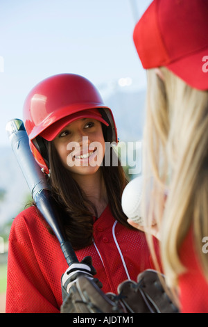 Giovane donna holding softball bat a parlare con il compagno di squadra Foto Stock