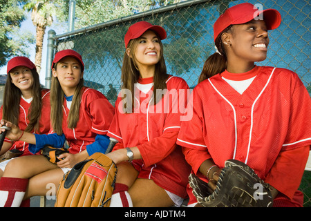 Femmina giovane softball giocatori seduti su un banco di lavoro Foto Stock