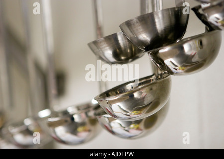 Varie dimensioni di mestoli appesi da rack nella scuola di cucina Foto Stock