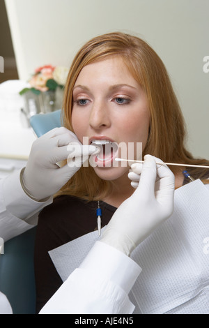 Giovane donna avente denti esaminati presso i dentisti Foto Stock
