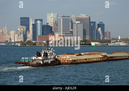 Rimorchiatore spinge una chiatta di fronte la parte inferiore di Manhattan Foto Stock