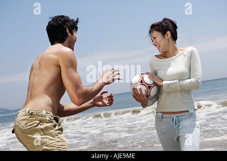 Coppia giovane giocando a pallavolo sulla spiaggia Foto Stock