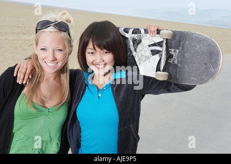 Due giovani donne skateboarders sulla spiaggia, ritratto Foto Stock