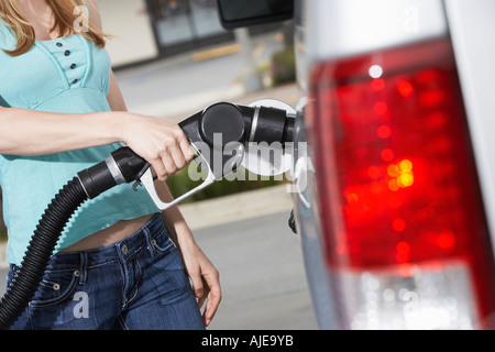 Giovane donna auto di riempimento con il gas a gas station, metà sezione Foto Stock