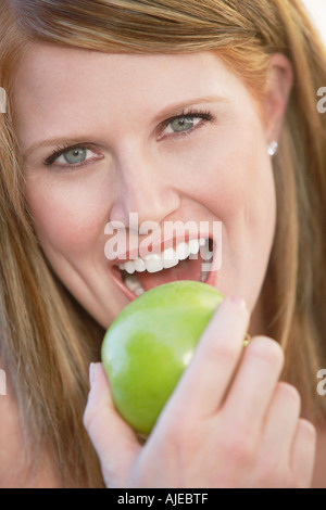 Donna prendendo boccone fuori di Apple, ritratto, (close-up), (verticale). Foto Stock