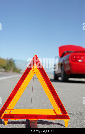 Il triangolo di avvertenza di fronte ripartiti automobile sportiva rossa a lato della strada Foto Stock