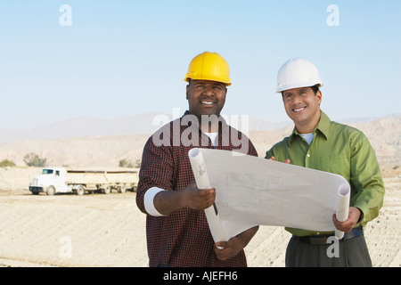 Lavoratori edili Indossare copricapi rigidi, guardando il piano sul sito Foto Stock