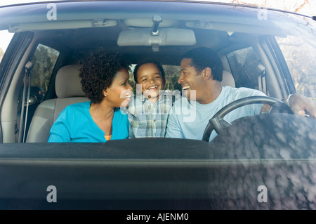 Coppia sorridente al giovane figlio in auto, vista attraverso il parabrezza Foto Stock