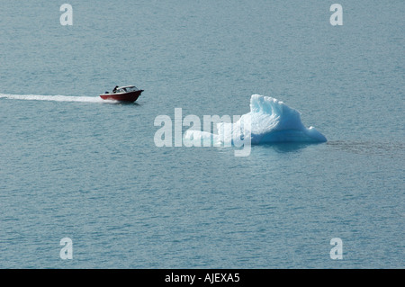 Una piccola imbarcazione a motore velocità passato un iceberg nella baia di Disko, Groenlandia Foto Stock