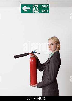 Imprenditrice azienda estintore sotto il segno di uscita Foto Stock