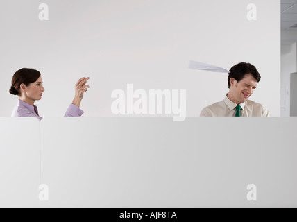 Donna gettando aeroplano di carta al collega di sesso maschile in office Foto Stock