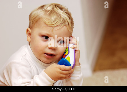 Ragazzo giovane finge di parlare sul giocattolo di telefono Foto Stock