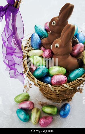 Uovo di Pasqua raccolta nel cesto di vimini con due conigli di cioccolato Studio shot Foto Stock