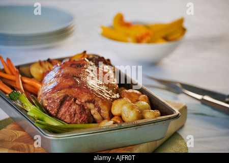 Arrosto di agnello e verdure in teglia su una tavola di legno Foto Stock