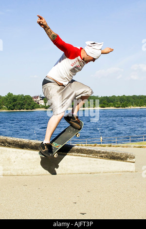 Teenage pratiche maschio salta trucchi e maneouvers su uno skateboard Foto Stock