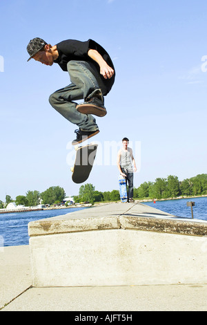 Teenage pratiche maschio salta trucchi e maneouvers su uno skateboard Foto Stock