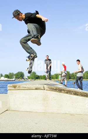 Teenage pratiche maschio salta trucchi e maneouvers su uno skateboard Foto Stock