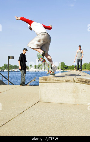 Teenage pratiche maschio salta trucchi e maneouvers su uno skateboard Foto Stock