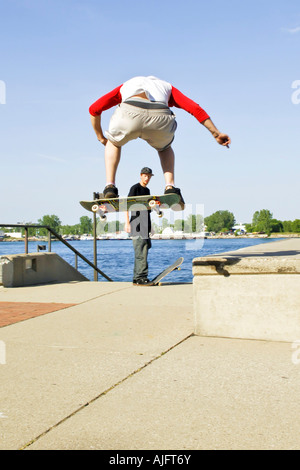 Teenage pratiche maschio salta trucchi e maneouvers su uno skateboard Foto Stock