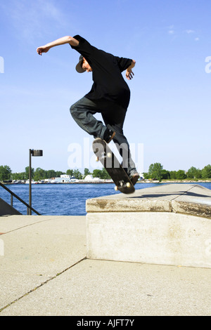 Teenage pratiche maschio salta trucchi e maneouvers su uno skateboard Foto Stock